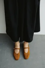 Ballerinas de gamuza color marrón con punta redondeada y tira trenzada ajustable en el empeine con hebilla metálica.