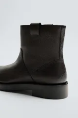 Bota de cuero con acabado abatanado, diseño de caña media, horma redonda y suela de goma con volumen a contraste.