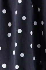 Vestido corto negro con estampado de lunares blancos. Diseño strapless con escote corazón y peplum superpuesto con efecto globo en la cintura.