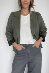 Chaqueta corta de diseño abierto, confeccionada en tejido con textura efecto ante. Presenta solapas clásicas, mangas largas con puños en contraste y un corte holgado y liviano.