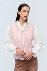 Chaleco de punto color rosa con escote en V y detalles en color beige.