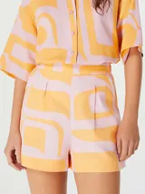 Short de tiro alto con diseño estampado en tonos naranja y rosado, con pinzas frontales y cierre lateral.