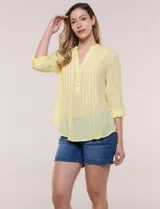 Blusa de gasa bambúla color amarillo, marca Zac & Rachel, con cuello a la base y escote en V con botones frontales. Presenta diseño delantero plisado y mangas largas con sistema de ajuste mediante presilla.