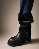 Bota de caña alta slouchy combinada de cuero marrón oscuro en la puntera y gamuza en el cuerpo principal de la caña. Cuenta con suela track gruesa de goma negra y detalle de tira con hebilla en el lateral inferior.