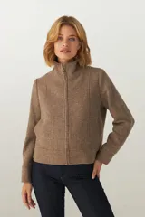 Campera de lana fina sin teñir, con cuello alto, cierre frontal completo y diseño de corte recto con pespuntes decorativos en puños, ruedo y cuello.