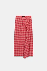 Falda midi de tiro medio, con estampado a cuadros vichy en tonos rojo y rosado, detalle de volantes en el delantero y cierre lateral con cremallera oculta.