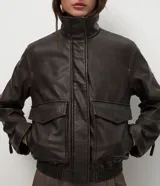 Campera de cuero sintético marrón con efecto desteñido, cuello alto y solapa de piel sintética desmontable. Cuenta con cierre frontal, bolsillos delanteros con solapa y elástico en el ruedo.