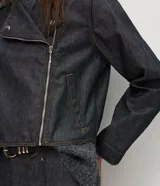 Campera estilo biker confeccionada en denim oscuro, con diseño estructurado, cuello con solapas, cierre frontal asimétrico y botones a presión metálicos.