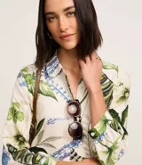 Vestido chemise midi confeccionado en viscosa sostenible, con cuello, abotonadura frontal, recorte en la cintura y bajo fruncido. Presenta un estampado floral con follajes.