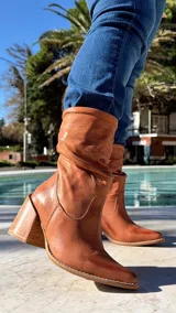 Bota alta de cuero color marrón, con efecto fruncido en la caña y taco ancho cuadrado.