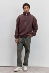 Buzo de cuello alto con cierre frontal parcial, de corte holgado y diseño minimalista con pequeño estampado central en el pecho.