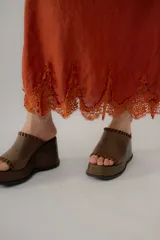 Vestido largo de lino blanco con tirantes finos, escote en V y detalle de encaje transparente en la parte inferior y en el escote.