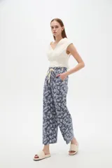 Pantalón de algodón estampado con diseño botánico de hojas en tonos verdes sobre base blanca, de corte holgado, tiro medio y cintura elástica con cordón de ajuste ajustable.