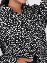 Camisa de manga larga con estampado abstracto en blanco y negro, con cuello clásico y cierre frontal con botones. Corte holgado.