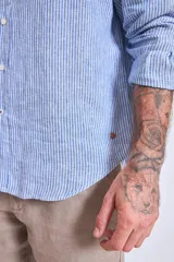 Camisa de corte regular con diseño de rayas verticales finas en tonos claros, cuello clásico y mangas largas con puños abotonados.