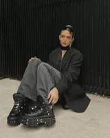 Borcego negro de cuero con plataforma track y detalles metálicos. Ajuste con cordones y hebillas.