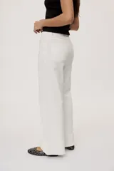 Pantalón de tiro medio y corte wide leg color beige, con diseño clásico de cinco bolsillos, presillas para cinto y cierre frontal con botón y cremallera.