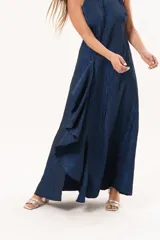 Vestido largo azul de tafeta con textura corrugada, cuello halter, espalda descubierta y falda amplia con tajo lateral y volados.