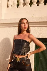 Top strapless de cuero metalizado color dorado, con diseño de tablones verticales en el frente que aportan estructura y elástico en la espalda para un ajuste cómodo.