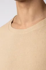 Remera de corte oversize confeccionada en tejido texturado tipo lino, de color beige, con cuello redondo amplio y mangas cortas de calce relajado.