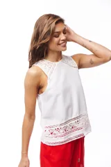 Blusa blanca sin mangas con detalles de encaje en el ruedo y los hombros.