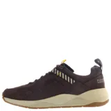 Championes de estilo urbano Caterpillar, confeccionados en gamuza color marrón tierra. Presentan una suela robusta de goma en tono beige y marrón, con detalles de cintas decorativas en amarillo y negro en la lengüeta y laterales.