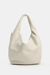 Bolso de hombro de gran tamaño color beige, con diseño hobo de líneas suaves, asa ancha integrada y cierre superior con imán.