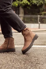 Bota de caña baja confeccionada en cuero vacuno encerado color taupe. Presenta un diseño de cuero blando con aspecto texturizado, cierre lateral y suela cosida de goma con relieve.