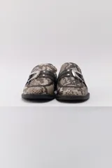 Mocasines de cuero con estampado animal print, detalle de hebilla plateada y suela plana.