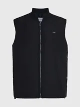 Chaleco negro acolchado con cuello alzado, cierre de cremallera, bolsillos con botón a presión y logo de Calvin Klein en el pecho.