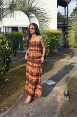 Vestido largo strapless, ajustado al cuerpo, con estampado batik en tonos marrones y naranjas.