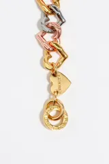 Collar de cadena tricolor con eslabones en forma de corazón entrelazados en tonos dorado, plateado y rosado. Presenta un cierre de barra T y un pequeño dije de corazón con logo grabado.