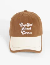 Gorra de béisbol color marrón con visera beige y bordado frontal con la frase "Breakfast Lunch Dinner".