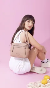 Bandolera color nude con cierre principal, bolsillos interiores, un bolsillo frontal y otro posterior con cierres, y bolsillos laterales. Incluye correa extensible.