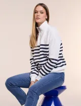 Buzo de frisa blanca con rayas horizontales azul marino, cuello alto con medio cierre y mangas largas.