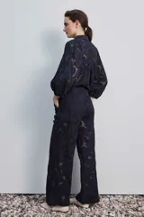 Pantalón largo negro de encaje con diseño floral calado, de tiro alto y corte recto.