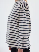 Remera de manga larga con calce holgado, confeccionada en algodón. Presenta un diseño a rayas horizontales en tonos beige y negro, con bordado de letras SP en el pecho y estampa de la marca en la manga.