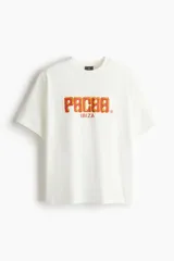 Remera de algodón color blanco con cuello redondo y mangas cortas. Presenta un estampado frontal con el logo de Pacha Ibiza en tonos naranja y amarillo.