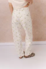 Jean de tiro alto confeccionado en denim color crudo, con estampa de estrellas en tono camel. Presenta calce relajado, pierna recta levemente amplia, costuras verticales delanteras, cinco bolsillos, pasacintos y detalle metálico en la parte posterior.