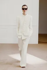 Blazer cruzado Zara Woman Collection confeccionado en hilatura de viscosa, de color blanco. Presenta cuello alto, manga larga con abertura y botones, bolsillos delanteros y cierre frontal cruzado con botones.