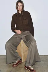 Zapatillas deportivas de caña baja con combinación de colores y materiales. El cuerpo principal es de color bordó, con refuerzos en gamuza marrón y detalles en color crema. La suela es de goma marrón. El cierre es mediante cordones gruesos color crema.