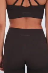 Calza deportiva de tiro alto color marrón, con diseño de perforaciones láser en la parte inferior de las piernas.