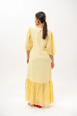 Vestido largo amarillo mantequilla con escote en V, mangas abullonadas y volados en el bajo con detalles de broderie.