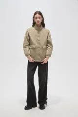 Campera acolchada de poliamida en color beige, con diseño de costuras en rombos, cuello alto, cierre frontal y bolsillos delanteros con solapa.