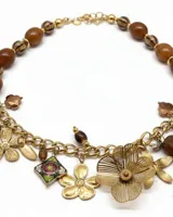 Collar corto con cuentas de madera y resina, decorado con una cadena frontal que sostiene un mix de dijes colgantes en forma de flores y figuras geométricas. Incluye cierre de mosquetón con cadena de alargue.