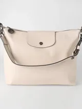 Cartera hobo grande Longchamp de la línea Le Pliage Xtra, confeccionada en cuero color gris claro, con solapa frontal con cierre de botón a presión y correa ajustable para el hombro.