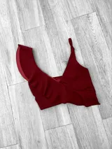 Top de bikini fucsia con un solo tirante y volados en el escote.