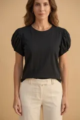 Remera de algodón color negro, con cuello redondo y mangas cortas abullonadas tipo globo con detalles fruncidos en los hombros.
