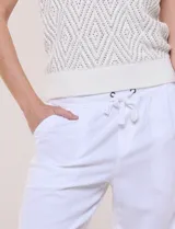 Pantalón de lino blanco marca Dash, de corte fluido, con pretina elástica y cordón ajustable en la cintura. Cuenta con bolsillos delanteros inclinados y traseros aplicados.