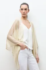 Ruana de tejido abierto con hilo de lurex dorado, diseño amplio y caída ligera.